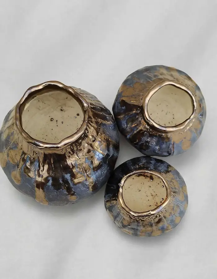 Three metallic lustre-glazed pots viewed from above, gold rims catching light
