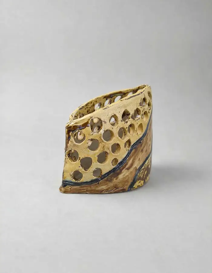 Perforated honeycomb-textured vessel in olive and gold glaze with a dark rim