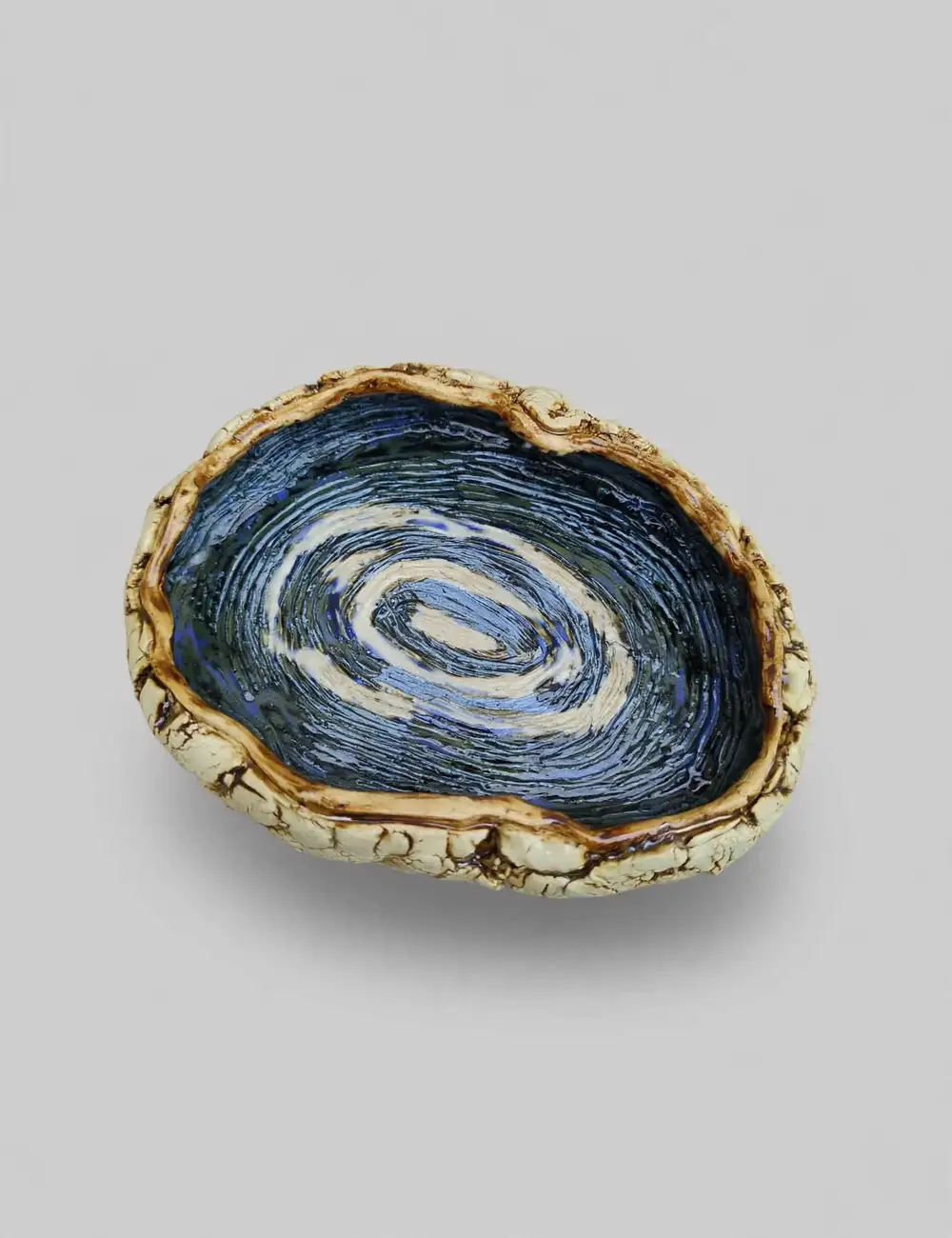 Ceramic bowl with a crackled cream rim and a deep blue spiral-combed interior