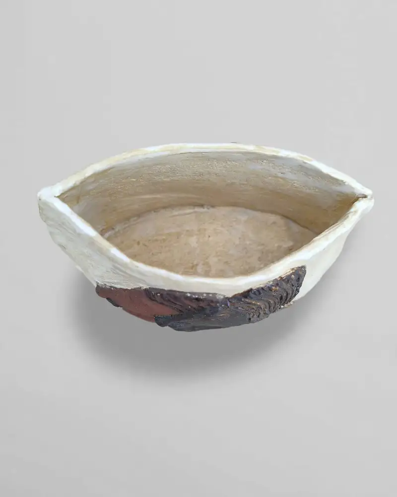White ceramic boat-shaped dish with a dark textured accent at one tip