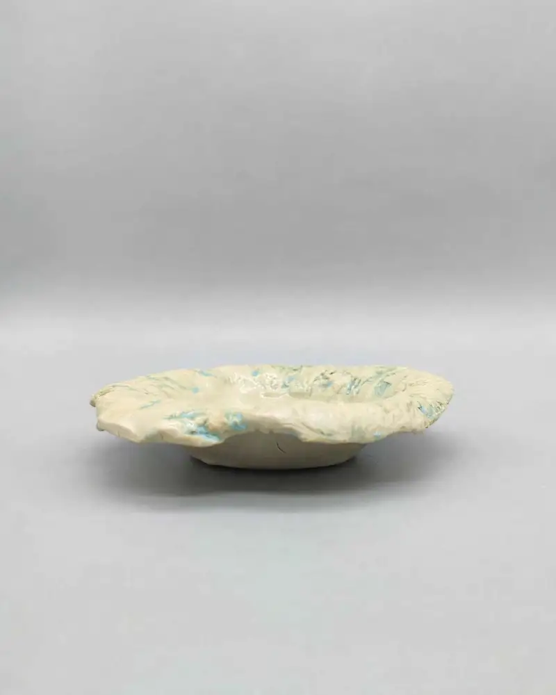 Pale wavy-rimmed ceramic dish with soft blue-green glaze flecks